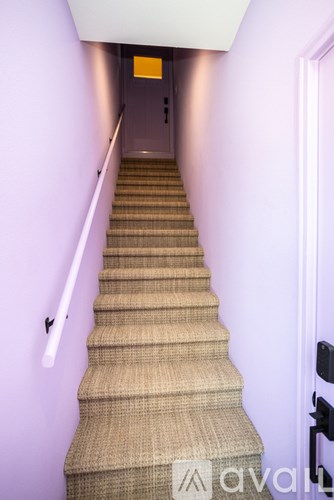 A staircase with a beige carpeted runner and a black handrail.