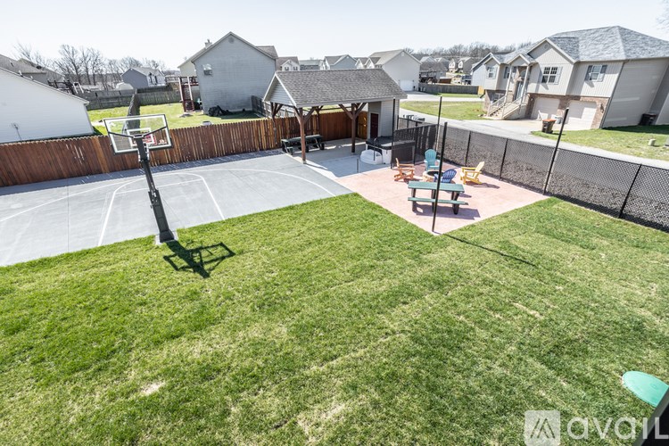 A backyard with a basketball hoop and a fence.