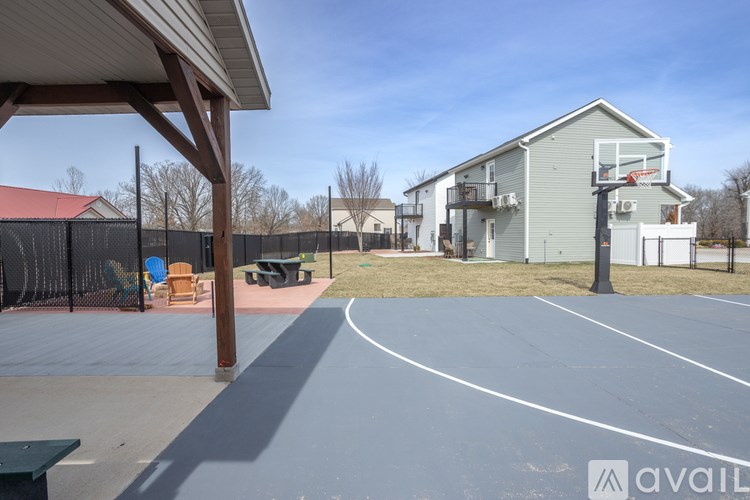 A basketball court is located in a residential area with a basketball hoop and a building in the background.