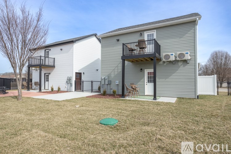 A two-story building with a balcony and a small garden in front.