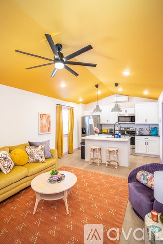 A living room with a yellow couch and a ceiling fan.