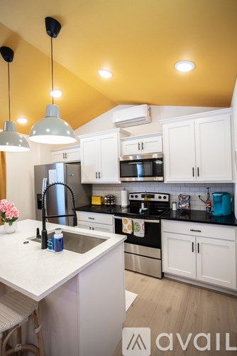 A kitchen with white cabinets and a black countertop.