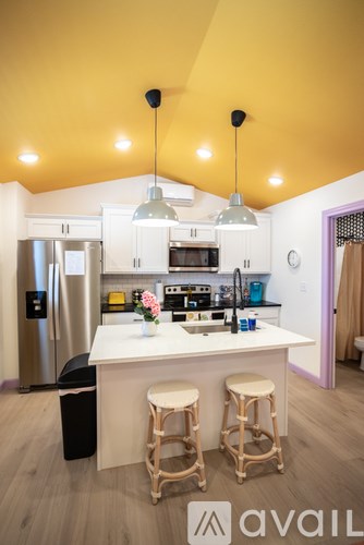 A kitchen with a white counter and bar stools.