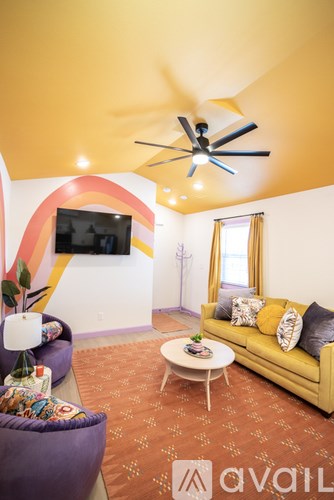 A living room with a yellow couch and a ceiling fan.