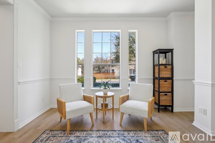 A living room with a table and chairs in front of a window.