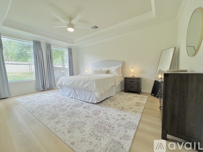 A bedroom with a large bed and a ceiling fan.