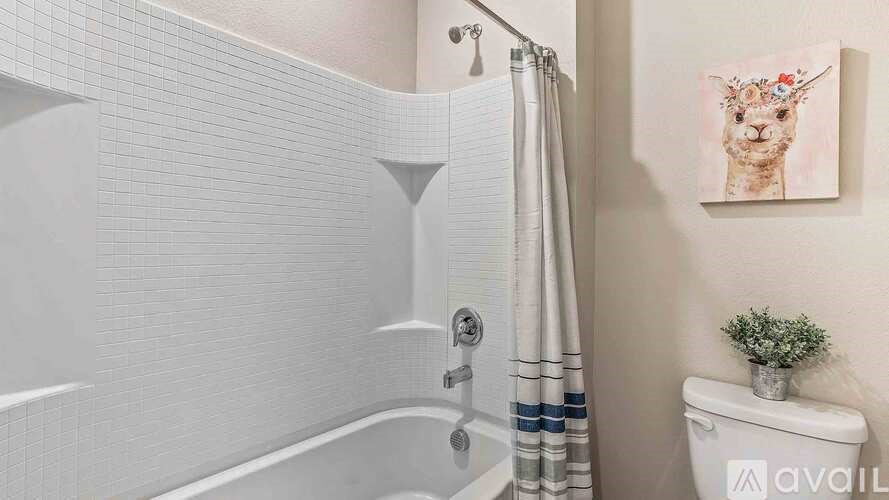 A bathroom with a white tub, a toilet, and a painting of a cat on the wall.