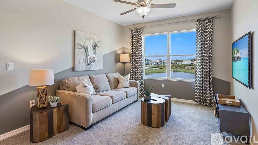 A living room with a grey couch, a wooden table, and a painting of a cow on the wall.