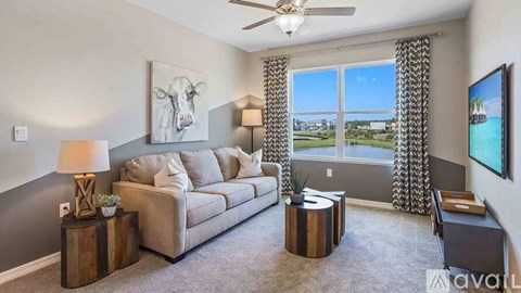 A living room with a grey couch, a wooden table, and a painting of a cow on the wall.