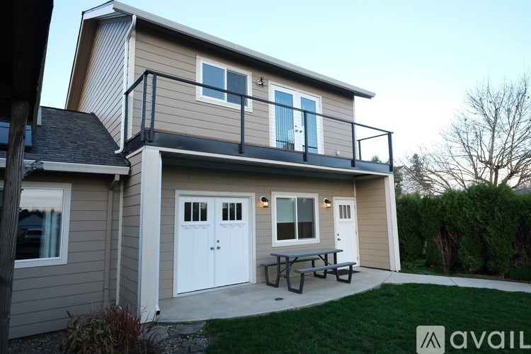 A house with a balcony and a picnic table in the yard.