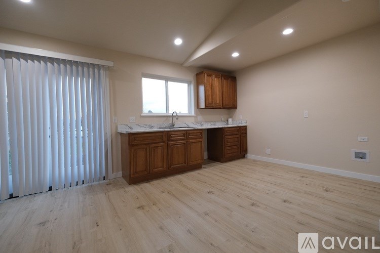 A kitchen with wooden cabinets and a window with blinds.