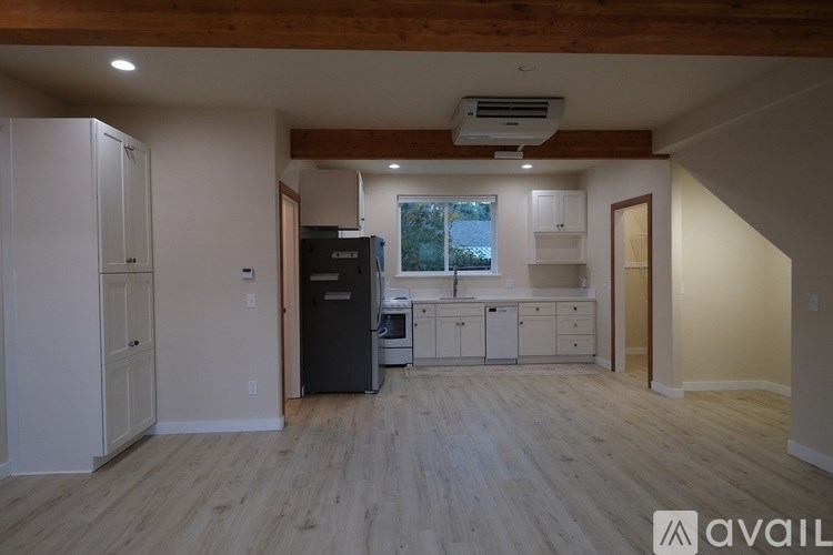 A kitchen with a black fridge and white cabinets.
