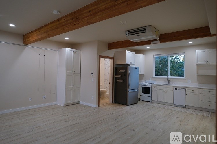 A spacious kitchen and living room with wooden floors and white walls.
