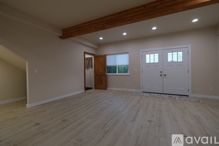 A spacious room with wooden floors and a large window.