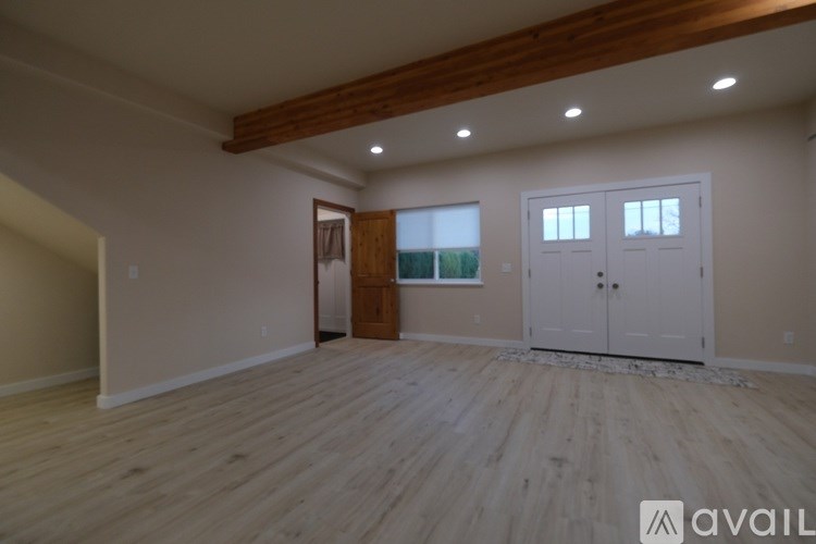 A spacious room with wooden floors and white walls is available for rent.