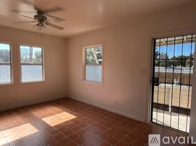 A room with a ceiling fan and tiled floor leading to a balcony.