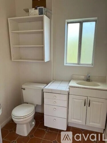 A white bathroom with a toilet, sink, and cabinets.
