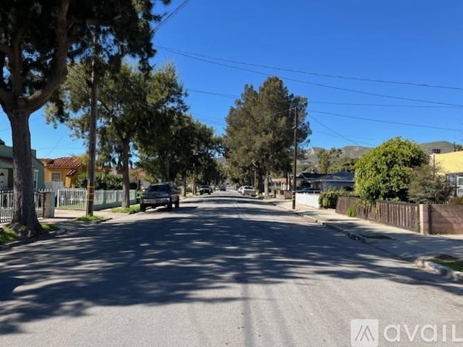 A street view with a car parked on the side and houses on both sides.