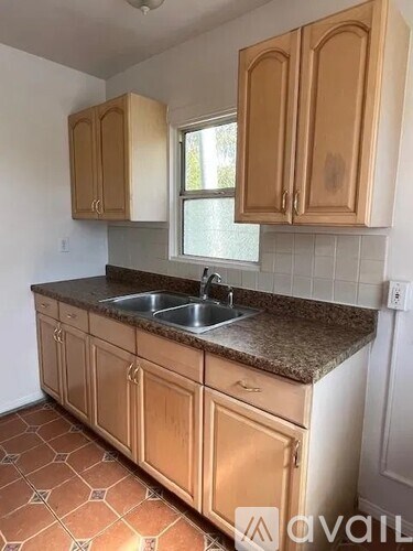 A kitchen with wooden cabinets and a tiled floor.