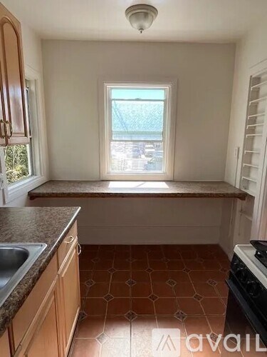 A kitchen with brown tiles on the floor and wooden cabinets.