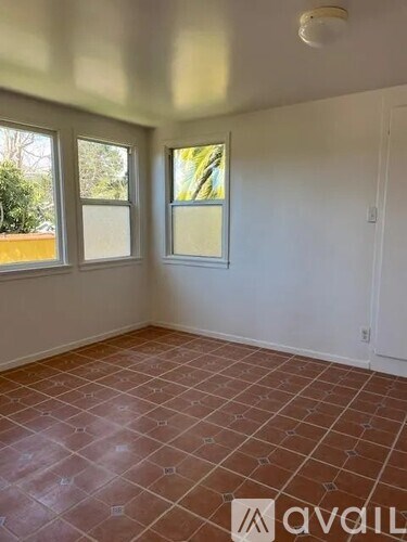 A room with tiled flooring and two windows.