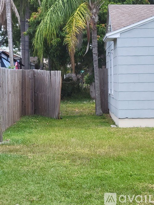A wooden fence separates a grassy area from a house.