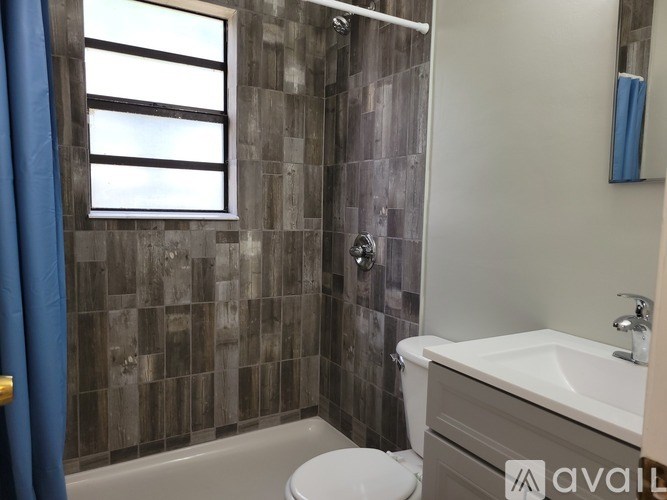 A bathroom with a white toilet, a white sink, and a shower with a blue curtain.