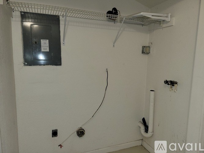 A white wall with a black electrical box and a white pipe.