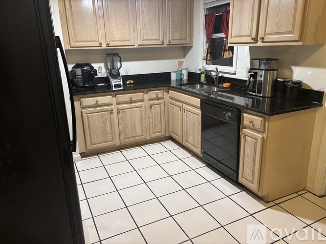 A kitchen with black countertops and white tile flooring.