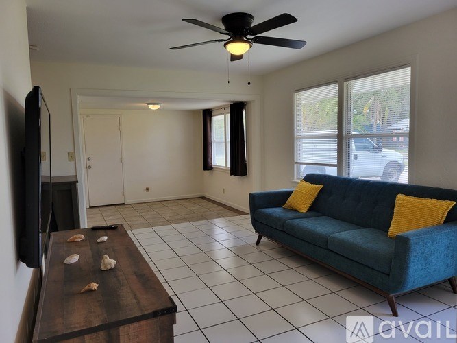 A living room with a blue couch and a television mounted on the wall.