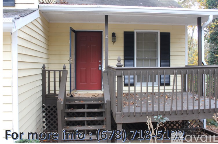 A yellow house with a red door and a wooden porch.