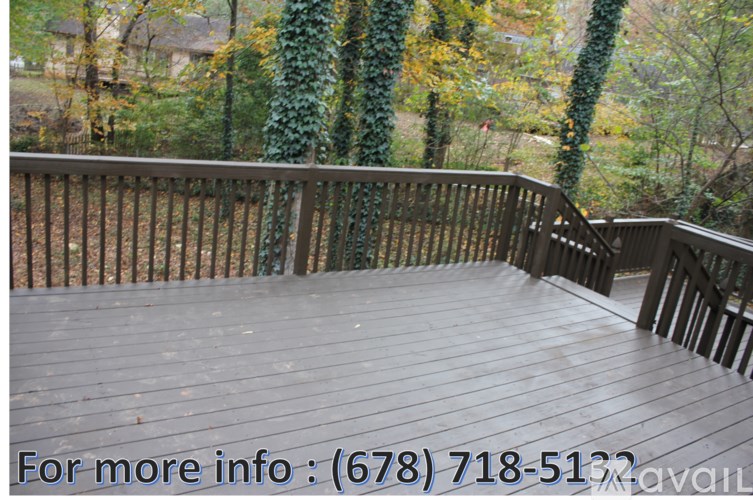 A wooden deck with a railing and ivy covered trees in the background.