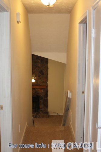 A hallway with a stone fireplace and a light on the wall.