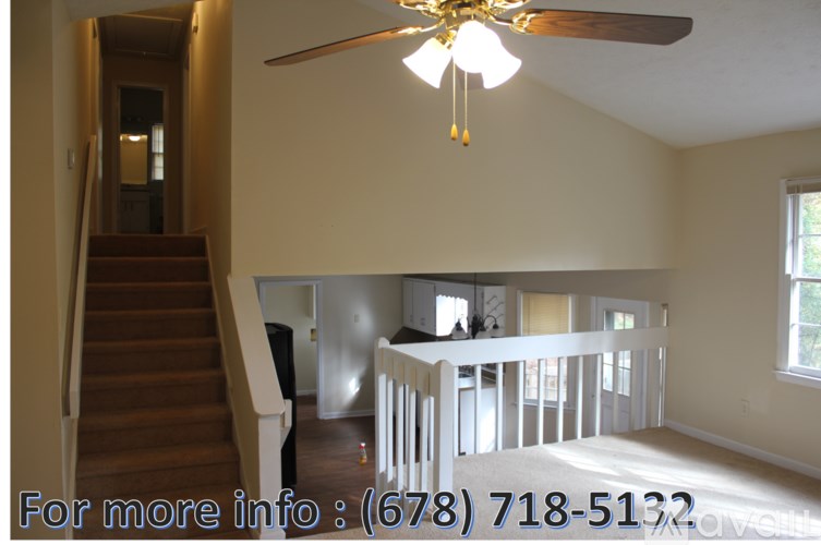 A living room with a staircase and a chandelier.