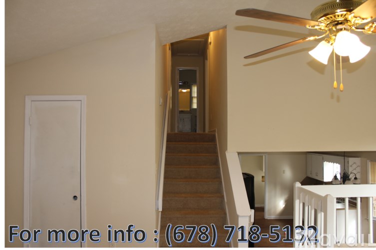 A room with a staircase and a ceiling fan.