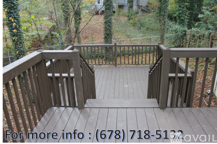 A wooden deck with a railing and steps leading to a forest.