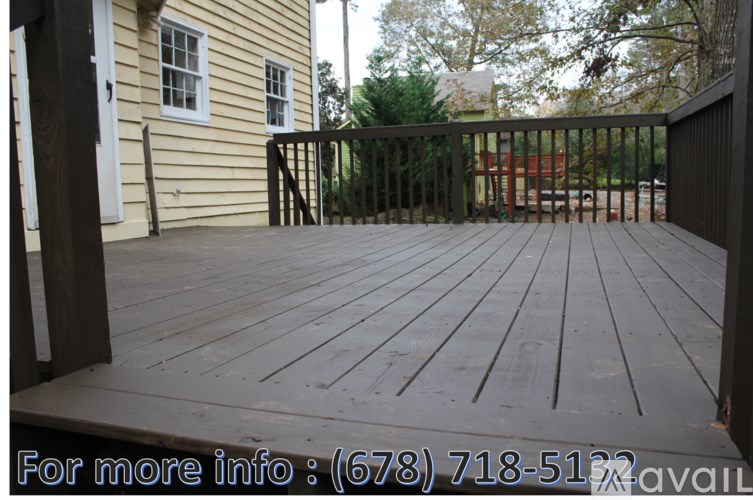 A wooden deck with a railing and a house in the background.
