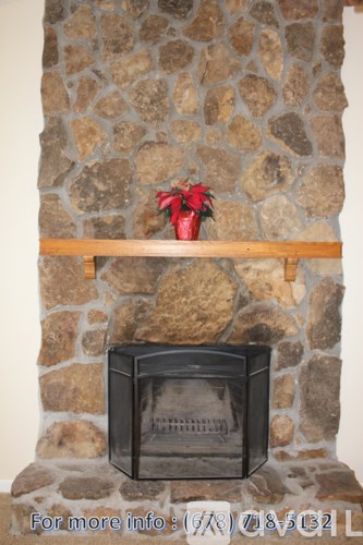 A black fireplace with a wooden shelf above it.