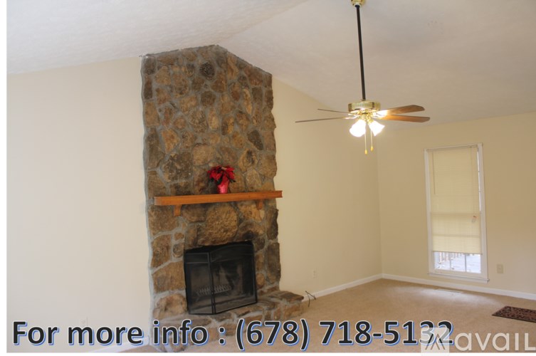 A room with a stone fireplace and a ceiling fan.