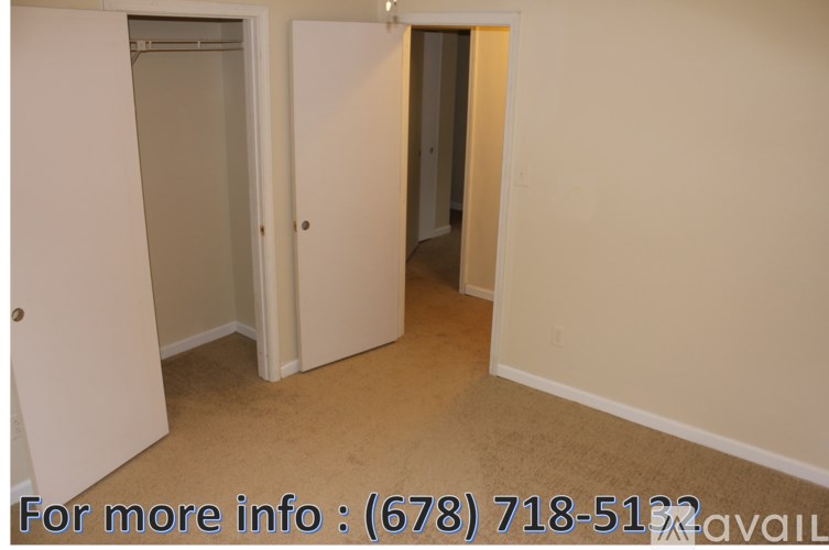 A room with a white door and a white wall with a phone number written on it.