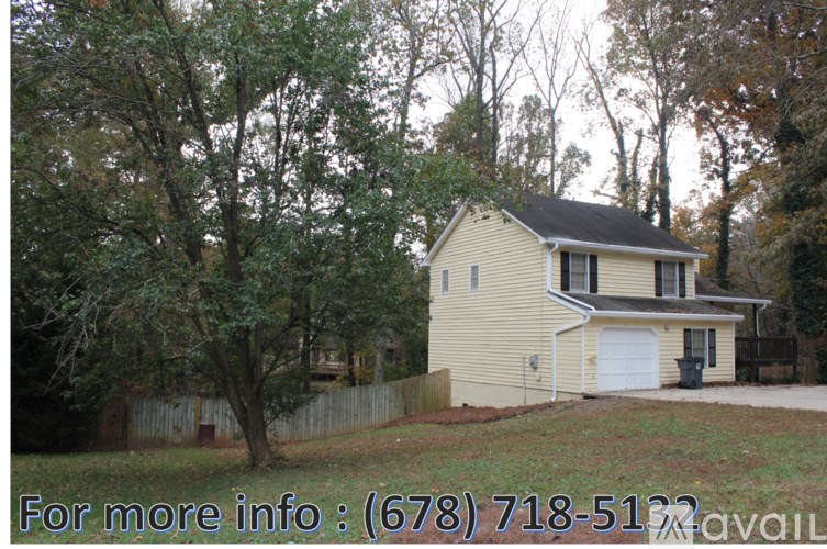 A house with a fence and trees in the background.