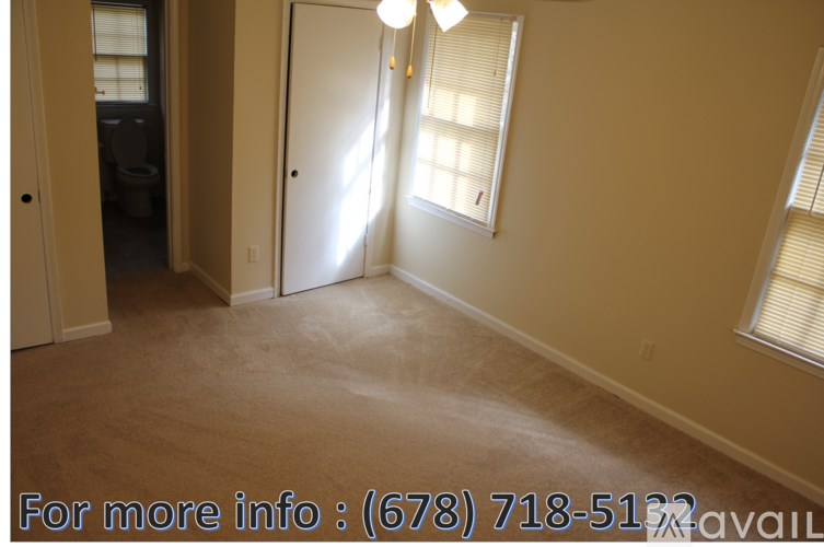 A room with a carpeted floor, a door, and a window with blinds.