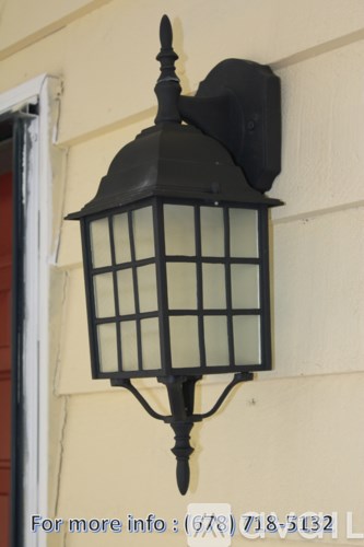 A black lantern with glass panels is mounted on a wall.
