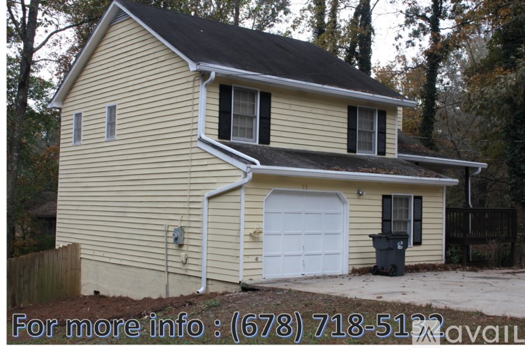 A house with a white garage door and a black trash bin outside.
