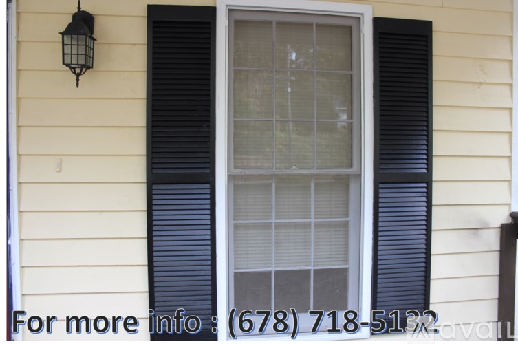 A window with black shutters and a lantern hanging on the wall.