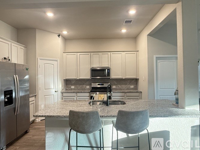 A modern kitchen with a refrigerator, microwave, and oven.