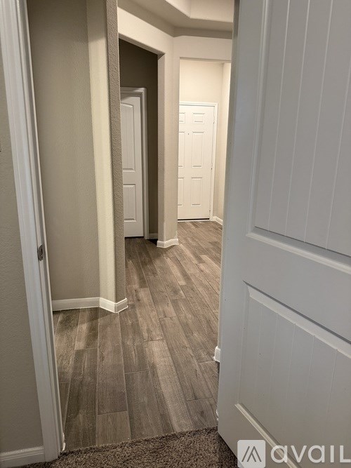 A hallway with a carpeted floor and white doors.