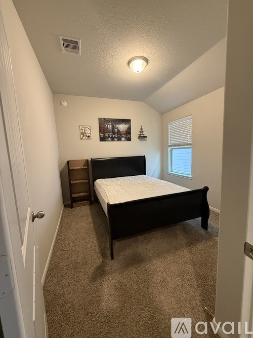 A bedroom with a bed, dresser, and window.