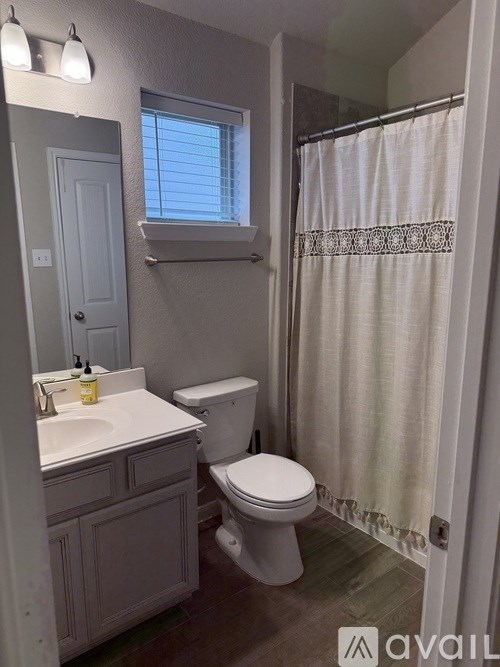 A bathroom with a toilet, sink, and shower.
