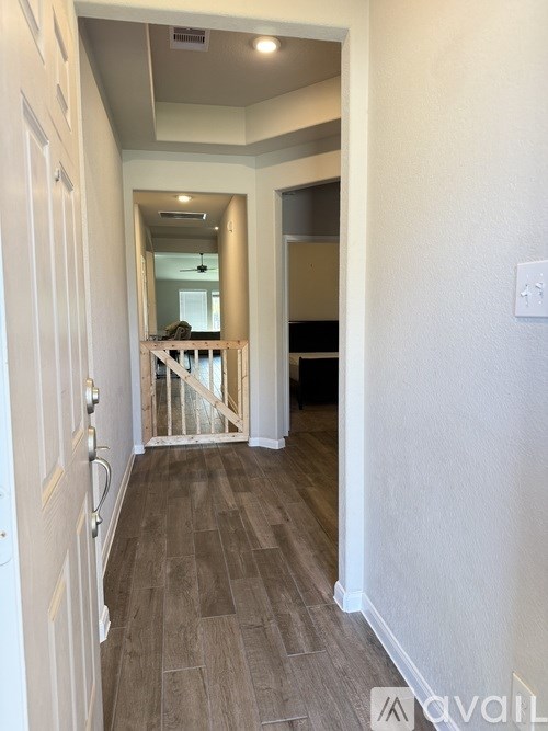A hallway with a wooden floor and white walls.